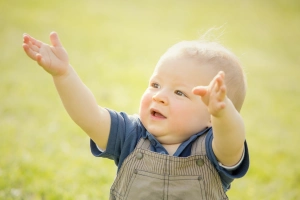 Kisfiú a réten felemelt kézzel 