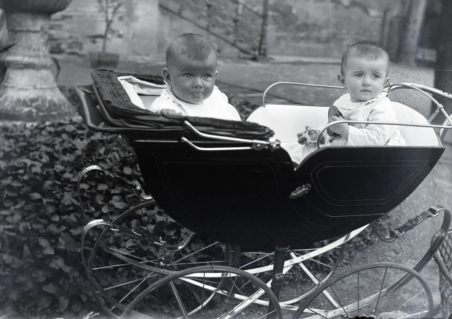 Két baba ül egy babakocsiban 